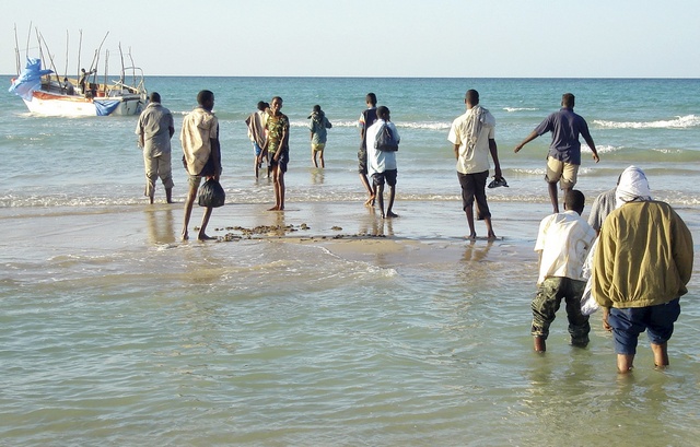 Illegal immigrants from Somalia walk to a vessel in port town of Bossaso